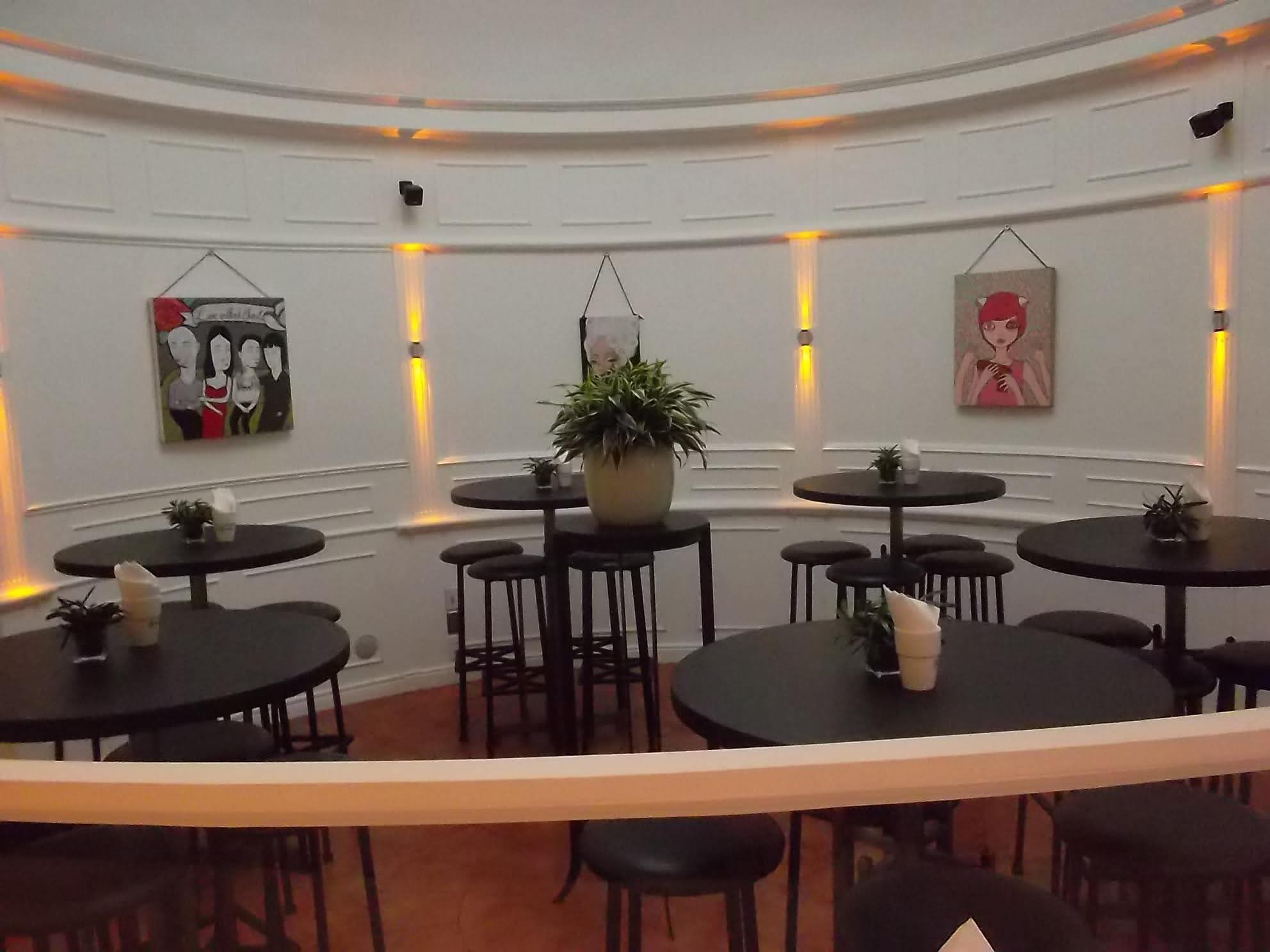 Round tables and warm wall lighting inside Café Escudero