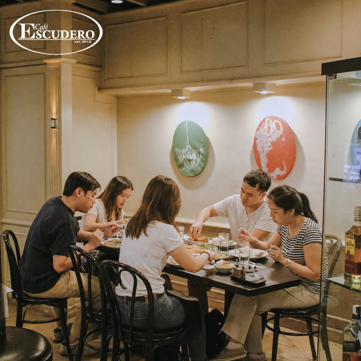Five guests eating together around a table inside Café Escudero